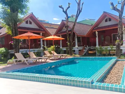 a swimming pool in front of a house with umbrellas at Tangerine Villa Patong in Patong Beach