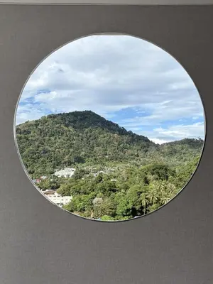 a round window with a view of a mountain at Luxury villa with sea view, pool and maid in Patong Beach
