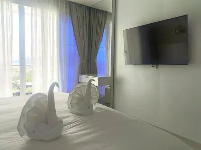 two white swans sitting on a bed with a flat screen tv at Luxury villa with sea view, pool and maid in Patong Beach