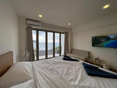 a bedroom with a large bed and a large window at Acacia Phuket in Nai Harn Beach