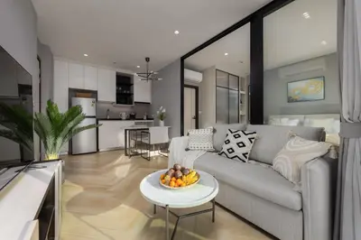 a living room with a couch and a bowl of fruit on a table at Delos 1BR Suite — The Title Legendary BangTao in Bang Tao Beach