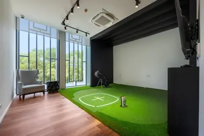 a room with a green carpet with a baseball field at Delos 1BR Suite — The Title Legendary BangTao in Bang Tao Beach