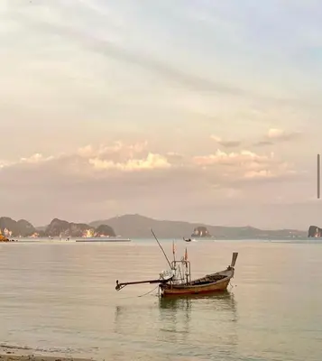 a small boat sitting in the water on the beach at Ja Mia's Bungalow at Pasai Beach in Ko Yao Noi