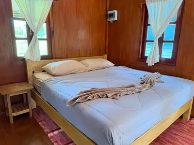 a bed in a room with wooden walls and windows at Ja Mia's Bungalow at Pasai Beach in Ko Yao Noi