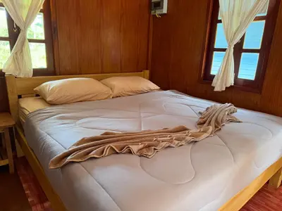a large bed in a room with two windows at Ja Mia's Bungalow at Pasai Beach in Ko Yao Noi