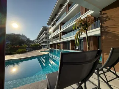 a swimming pool with a chair next to a building at Sunshine BEACH FRONT access to the pool in Layan Beach