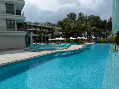 a large blue swimming pool next to a building at Sunshine BEACH FRONT access to the pool in Layan Beach