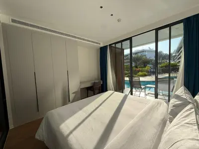 a bedroom with a bed and a view of a pool at Sunshine BEACH FRONT access to the pool in Layan Beach