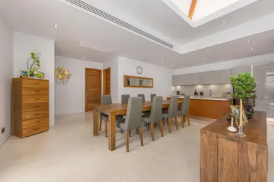 a kitchen and dining room with a wooden table and chairs at Private 3BR Pool Villa Mana at Anchan Tropicana in Ban Phru Champa