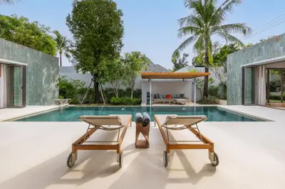 two chairs sitting next to a swimming pool at Private 3BR Pool Villa Mana at Anchan Tropicana in Ban Phru Champa