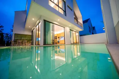 a swimming pool in front of a house at BangTao 4-Bedroom Brand New Modern Luxury Villa 2024 Minimalist Design Spacious 15-meter L-Shaped Swimming Pool Ideal for Guests in Laguna Phuket