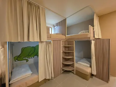two bunk beds in a room with a dinosaur painted on the wall at The Rock Poshtel Patong in Patong Beach