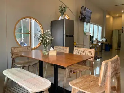 a dining room table with chairs and a refrigerator at The Rock Poshtel Patong in Patong Beach