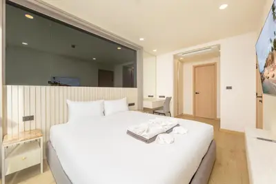 a bedroom with a white bed and a large mirror at Suite Salina 2BR Pool Gym Access Ozone in Laguna Phuket