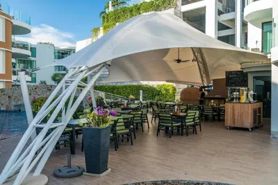 a patio with tables and chairs under a white umbrella at Resort Sea View Apartment Patong in Patong Beach