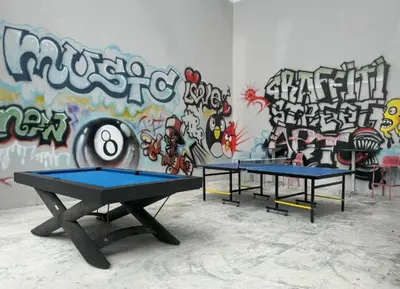 two ping pong tables in front of a wall with graffiti at Resort Sea View Apartment Patong in Patong Beach