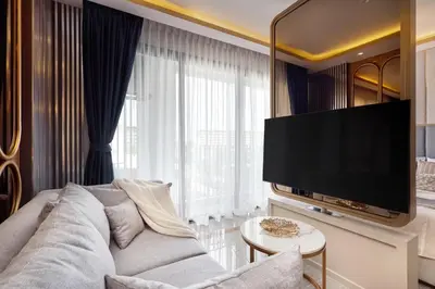 a living room with a couch and a flat screen tv at Bellevue Lagoon by My Home Phuket in Laguna Phuket