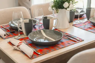 a wooden table with a table set with plates and wine glasses at Condo Close to the Beach and City Center in Laguna Phuket