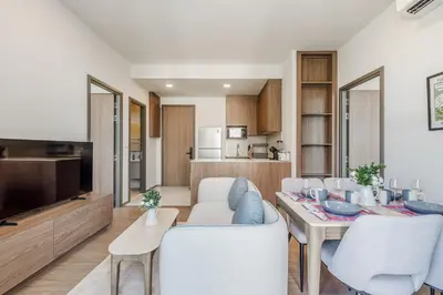 a kitchen and living room with a table and chairs at Condo Close to the Beach and City Center in Laguna Phuket