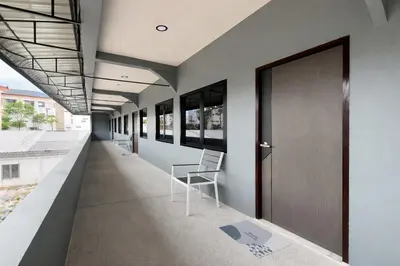 a corridor of a building with chairs and a door at The Homey Boutique Rawai in Ban Nong Chaeng