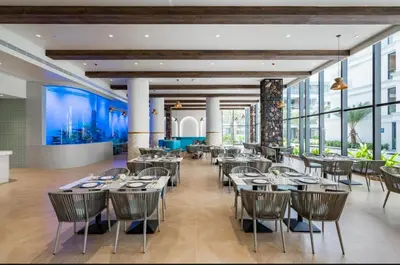 a dining room with tables and chairs and windows at Sunshine Layan Beach Resort 1 bedroom #84196 in Layan Beach