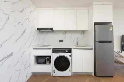 a white kitchen with a washer and dryer at Hydra 1BR Suite at Kora Beach Resort in Layan Beach