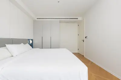 a bedroom with a white bed and an open door at Hydra 1BR Suite at Kora Beach Resort in Layan Beach