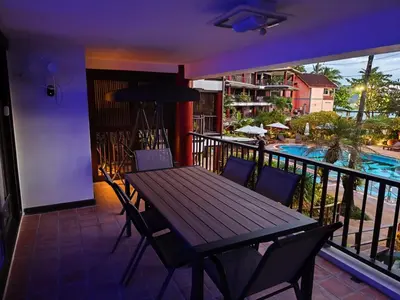 a balcony with a wooden table and chairs and a pool at Seaview paradise in Patong Beach