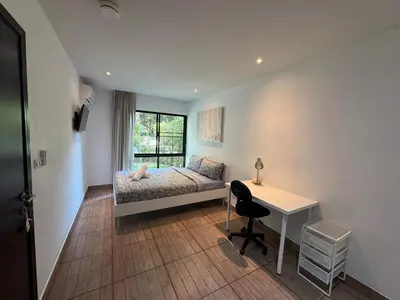a bedroom with a bed and a desk and a window at Apartment Title II, Rawai Phuket in Rawai Beach