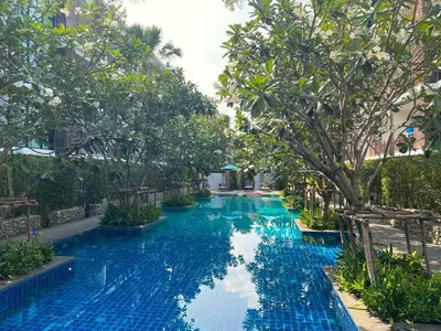 a pool at a resort with blue water and trees at Apartment Title II, Rawai Phuket in Rawai Beach