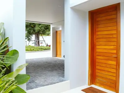 a hallway with a wooden door in a house at Anchan Flora Luxury 2BR Pool Villa in Thalang