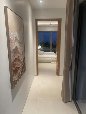 a hallway with a painting on the wall and a bedroom at Anchan Flora Luxury 2BR Pool Villa in Thalang
