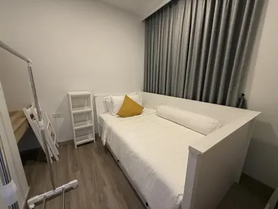 a bedroom with a white bed with a yellow pillow at Laguna cozy 2 bedroom apartment 5min to the beach in Laguna Phuket