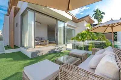 an outdoor patio with wicker chairs and an umbrella at V217 Brand New 3BR Villa Near Beach & Boat Avenue in Thalang