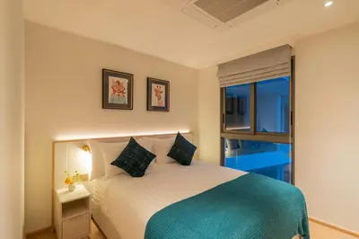 a bedroom with a bed with a blue blanket at Lakefront suite The Aqua at Boat avenue in Bang Tao Beach