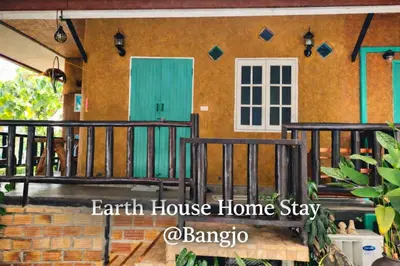 a house with a green door and a balcony at Earth House HomeStay Bangjo in Ban Pak Lak
