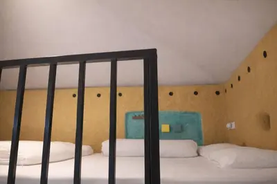 a bedroom with two beds and a wall with a staircase at Earth House HomeStay Bangjo in Ban Pak Lak