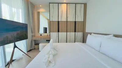 a bedroom with a white bed and a television at Phuvista Villas Naithon by Escape Villas - Brand New 3 BR Pool Villa - 500m from the beach in Phuket Town