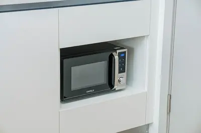 a microwave on a shelf in a white cabinet at Coastal 1 bd apartment - Moments from the sea in Layan Beach