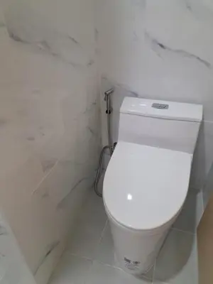a white toilet in a bathroom with marble walls at Bancha white house in Ban Bo Han