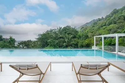 a swimming pool with two chairs and mountains in the background at Seavale patong phuket in Patong Beach