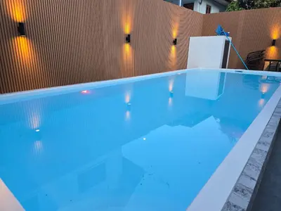 a swimming pool with blue water in front of a wall at Kathu V pool villa soi Srikor in Ban Kathu