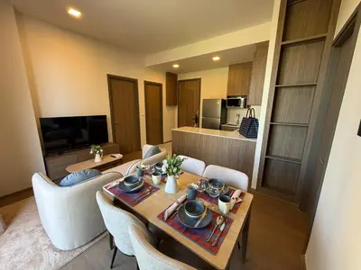 a living room with a table and chairs and a kitchen at Canvas Cherngtalay New 2BR Pool View Apartment in Laguna Phuket