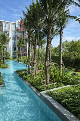 a pool with palm trees in a resort at 2BR Apartment, 10-Min Walk to the Beach in Laguna Phuket