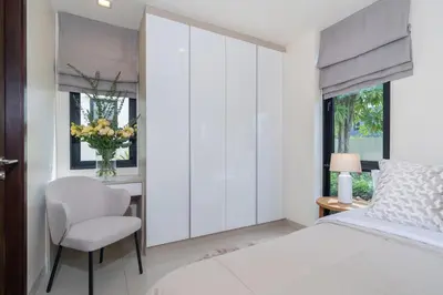 a bedroom with a bed and a chair and a window at Lux Laguna Park 5 bedroom rooftop pool in Laguna Phuket