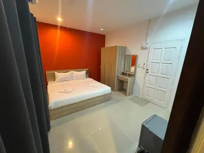 a small bedroom with a bed with an orange wall at Luxus Guesthouse in Patong Beach