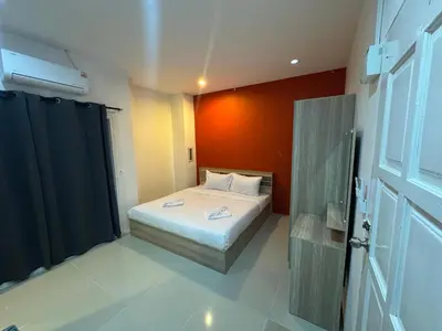 a small bedroom with a bed and an orange wall at Luxus Guesthouse in Patong Beach