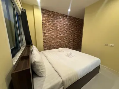 a small bed in a room with a brick wall at Luxus Guesthouse in Patong Beach
