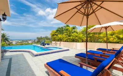 a swimming pool with blue chairs and an umbrella at Sea View Luxury Villas Kata Beach in Kata Beach