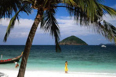 a woman standing on a beach with a palm tree at Sea View Luxury Villas Kata Beach in Kata Beach